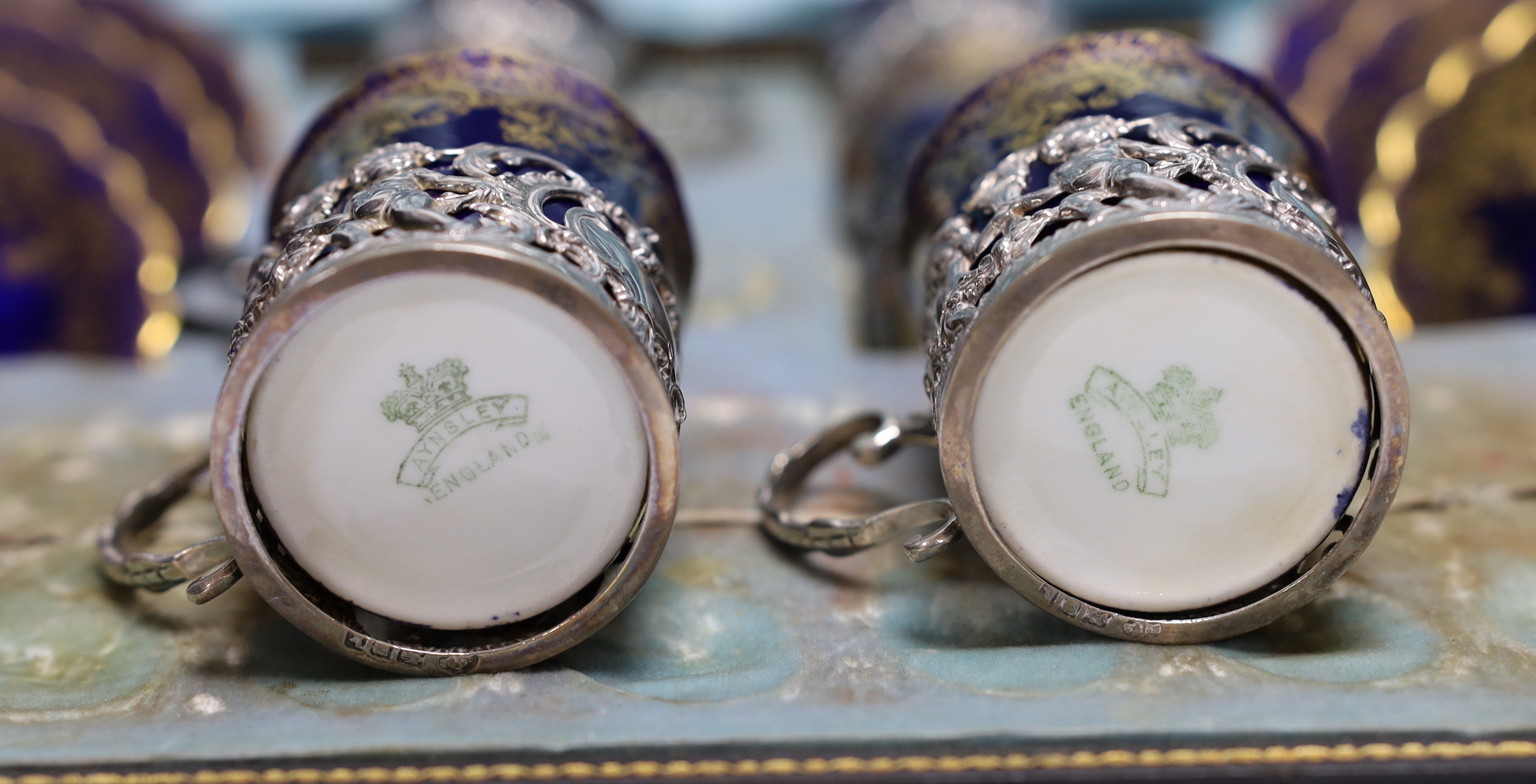 A set of eight Aynsley porcelain coffee cans and saucers, the cans with silver holders, William Hutton & Sons, London, 1905, with fitted case for six (no spoons)